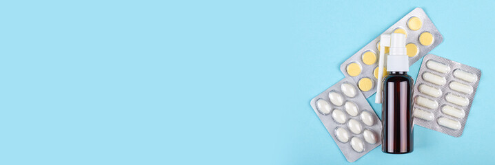 Throat spray bottle and pills on blue background. Flat lay, overhead view image.