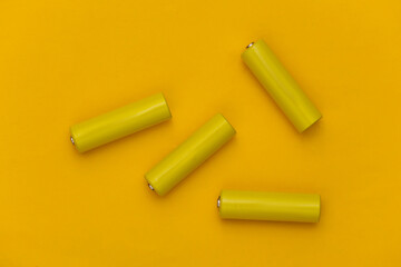 Four AA batteries on a yellow background. Top view