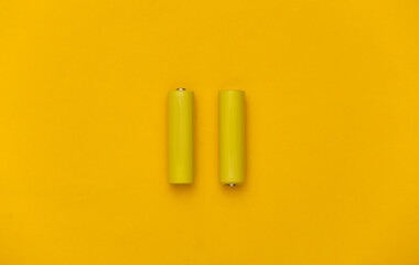 Two AA batteries on yellow background. Top view
