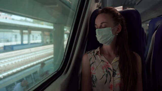 Woman in protective medical mask sleeping in train and awaking while arriving at the station. Precautionary measures in public transport and places, prevention coronavirus infection and spreading in