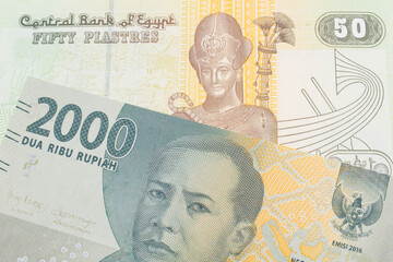 A macro image of a grey two thousand Indonesian rupiah bank note paired up with a green and yellow fifty piastre note from Egypt.  Shot close up in macro.