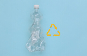 Recycled arrows sign and Plastic bottle on blue background. Eco concept. Top view