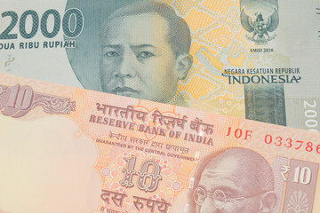 A macro image of a grey two thousand Indonesian rupiah bank note paired up with a orange ten rupee bill from India.  Shot close up in macro.
