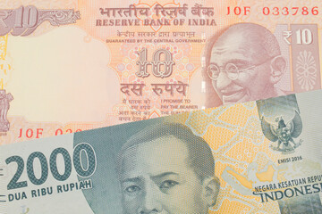 A macro image of a grey two thousand Indonesian rupiah bank note paired up with a orange ten rupee bill from India.  Shot close up in macro.