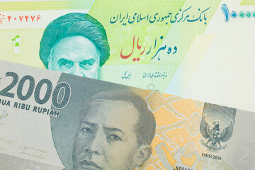 A macro image of a grey two thousand Indonesian rupiah bank note paired up with a blue and green ten thousand rial bank note from Iran.  Shot close up in macro.