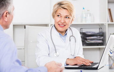 Doctor listens to mature patient and fills information card