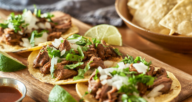 three carne asada mexican street tacos in corn tortilla with lime