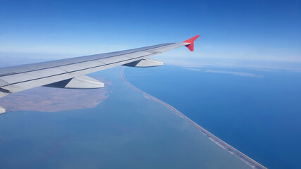 airplane wing above the clouds. Black sea coast view from the plane