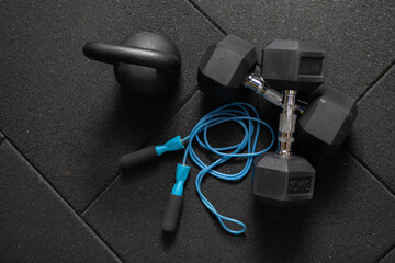 Functional training Sports equipment. Kettlebell and skipping rope, dumbbells on a dark black floor. Bodybuilding and fitness