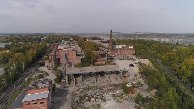 Aerial view of old factory. Red brick buildings and chimney. There is a railway on both sides of the plant. There is a huge quarry near the plant. Autumn sunny day
