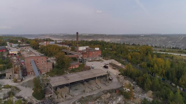 Aerial view of old factory. Red brick buildings and chimney. There is a railway on both sides of the plant. There is a huge quarry near the plant. Autumn sunny day
