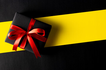 Top view of black christmas boxes with red ribbon on Yellow background with copy space for text. Cyber Monday composition or Black Friday, Boxing Day.