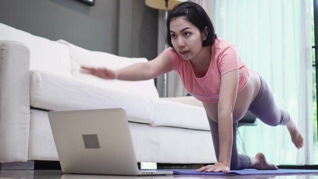 Asian pregnant woman doing yoga at home.