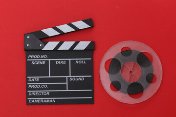 Movie clapper board and film reel on red background. Cinema industry, entertainment. Top view