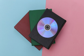 Stack of books and cd on blue-pink pastel background. Audio digital books