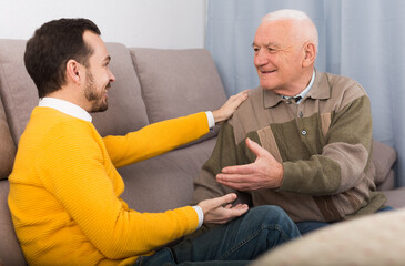 Mature father and adult son happy to spend time together at home