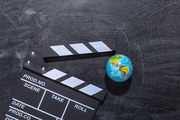 Movie clapper board and globe on chalk blackboard. Cinema industry, entertainment
