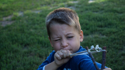a boy playing with a handmade slingshot