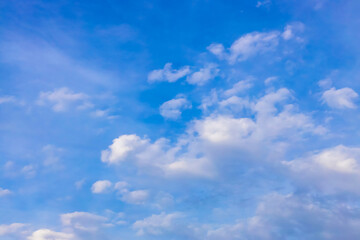Naklejka na ściany i meble Abstract atmospheric background. Delicate clouds in the blue sky. The sun illuminates the clouds from the side.