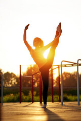 Stretching fit or dancer woman doing vertical split, twine in workout sports ground. Dancer silhouette at sunset