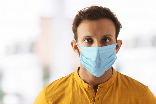 Portrait of a young man taking precautions by wearing a mask	