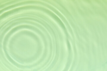 Closeup of mint green transparent clear calm water surface texture with splashes and bubbles. Trendy abstract summer nature background. Mint colored waves in sunlight. 