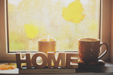 cozy autumn morning at home. Hot tea and candle on window in rainy cold day. Spending holidays at home.