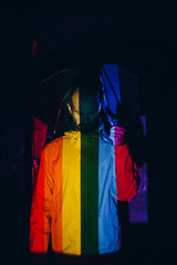 Rainbow Flag on body of adult man in dark with umbrella