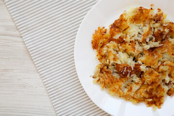 Homemade Fried Hashbrowns on a white plate, top view. Flat lay, overhead, from above. Copy space.