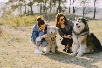 Women in a spring forest. Girls with cute dogs. Stylish friends walks.