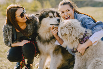 Obraz premium Women in a spring forest. Girls with cute dogs. Stylish friends walks.