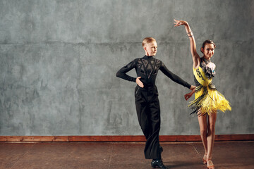 Young couple sport dancers dancing in ballroom dance cha-cha-cha. - obrazy, fototapety, plakaty