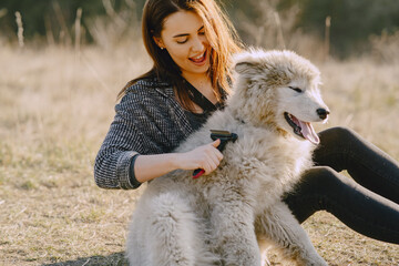 Woman in a spring forest. Girl with cute dog. Brunette in a gray jacket.