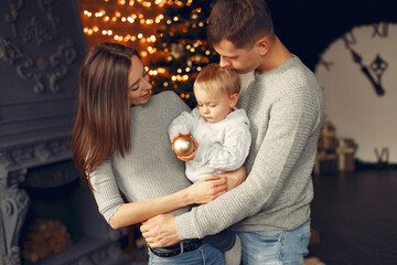 Mother in a gray sweater. Family with christmas gifts. People near fireplace.