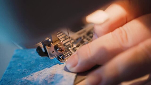 Grandmother sews square pieces of textile on a sewing machine. Close-up of sewing machine parts