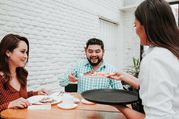 Owner mexican female waitress serving food to people sitting at restaurant in Latin america