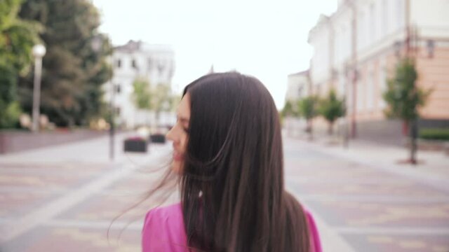 Cheerful caucasain female with long dark hair, pump lips, pretty face in pink dress goes for a walk and rejoices