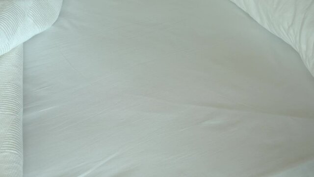 Closeup view of female hands making bed in bedroom