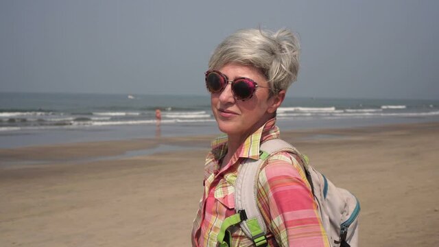 Portrait of an attractive mature woman tourist in sunglasses on the background of the sea