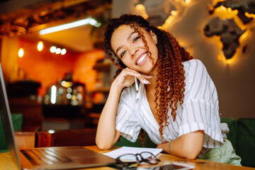 Young freelancer woman using laptop computer sitting at cafe table. Smiling woman working online or studying and learning while using notebook. Business People Concept