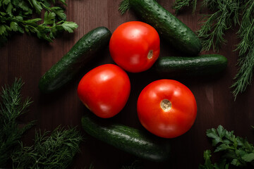 green cucumbers tomatoes and herbs on a wooden table