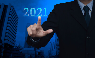 Fototapeta na wymiar Businessman pressing 2021 text over modern office city tower and skyscraper, Happy new year 2021 calendar cover concept