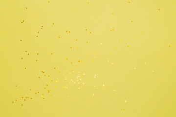 Yellow stars on a yelow background. Festive background of gold confetti stars.