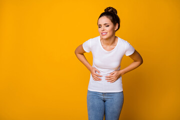 Frustrated stressed girl hipster have health care problem suffer abdominal menstruation pain touch her belly hands cry wear white t-shirt denim jeans isolated bright shine color background