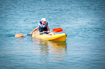 Fototapeta na wymiar kayaking lessons. Boy with life buoy suit in kayak lessons during summer vacations in an island of Greece.