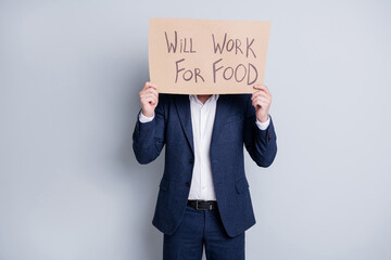 Fototapeta na wymiar Will work for food. Photo of worker dismissed guy suffer victim financial crisis lost work hold placard search work food exchange hide face expression wear blue suit isolated grey background
