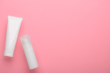 Skincare cream in white plastic tubes on a pink background flat lay. Set of cosmetic beauty products for skin cleansing and face care. Personal hygiene products top view with copy space