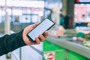 The guy is holding a smartphone with a white screen in the store.
