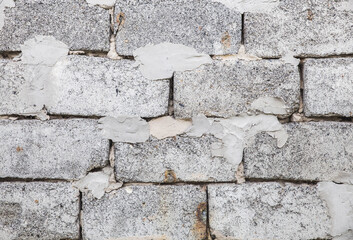 Gray rough wall made of cinder block unevenly smeared with cement