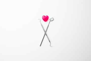 白い背景に置かれた歯科器具とピンクのハート
